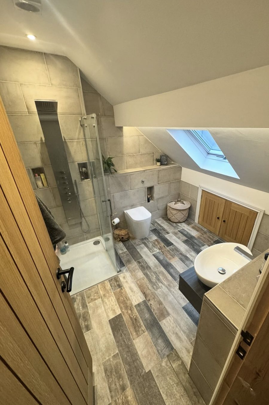Loft bathroom with a shower panel, walk-in shower, vessel basin and oak cupboard doors under the eaves