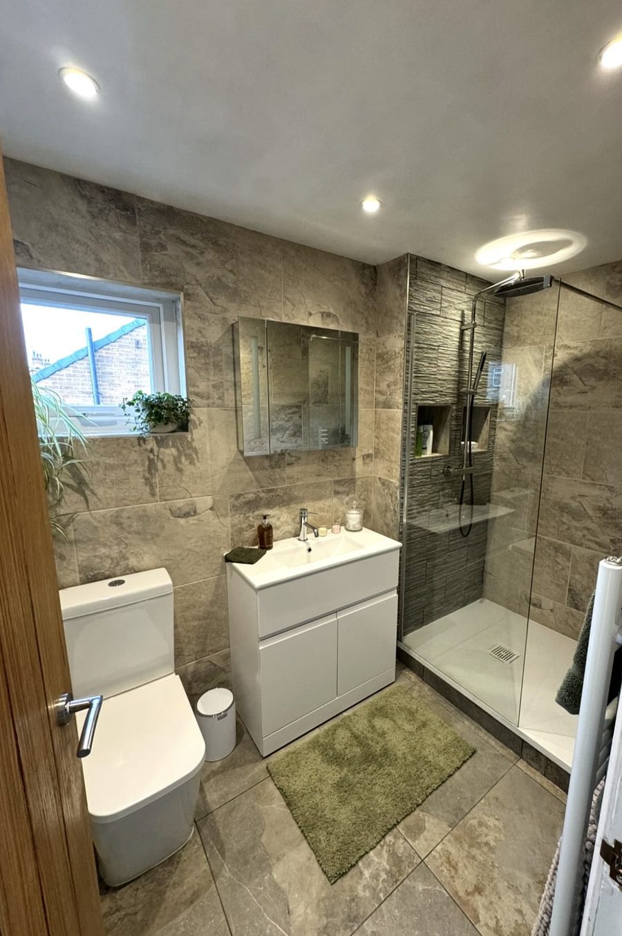 Bathroom with stone-effect tiles, a walk-in shower with a tiled niche, white vanity unit and mirror cabinet